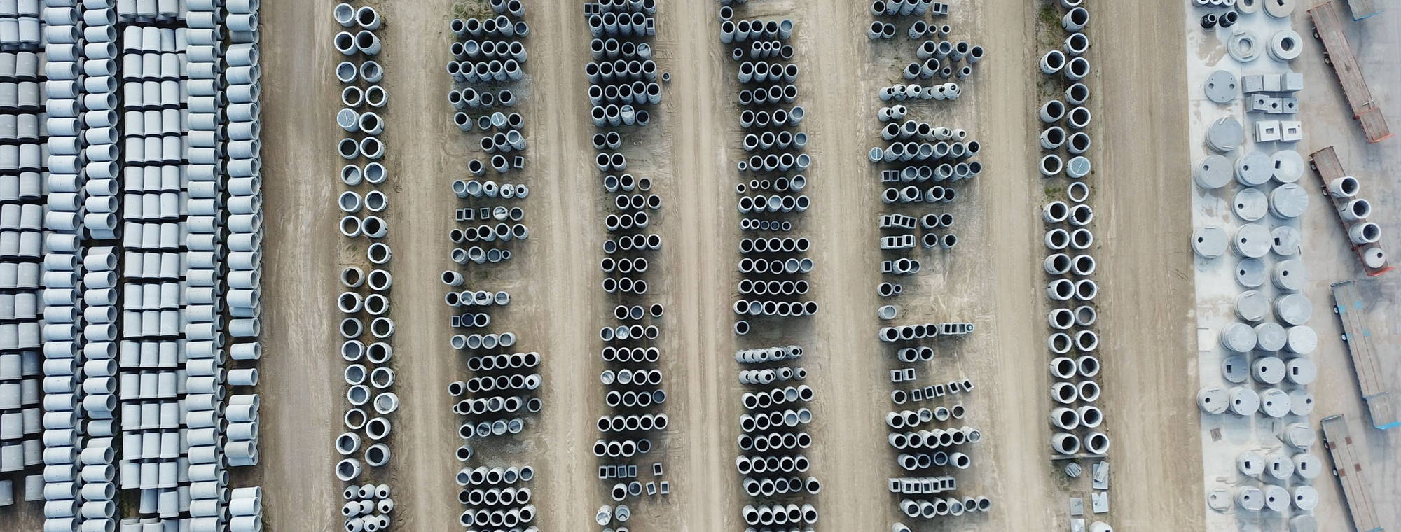 Precast pipes and culvert units stockpiled in rows at a laydown yard