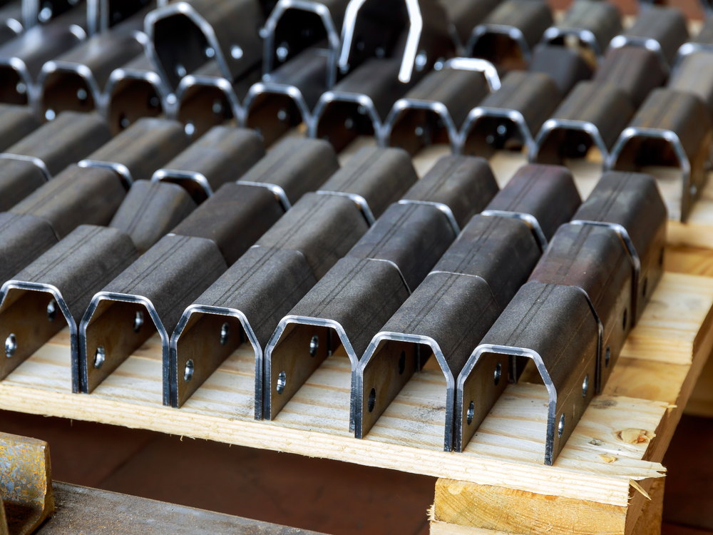 Rows of identical fabricated steel brackets on a workshop pallet