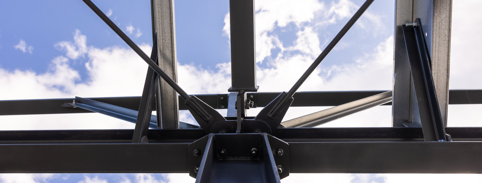 Structural steel truss connection seen from below against the sky